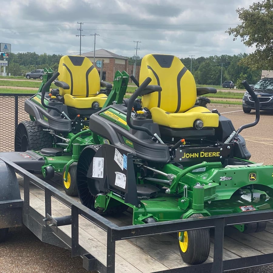Two commercial John Deere ZTrak zero-turn mowers loaded on the Clark Bros trailer