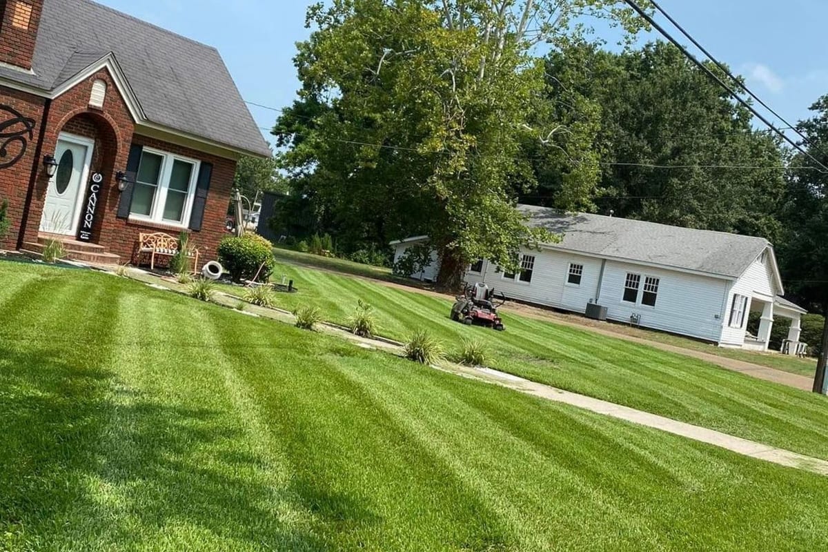 A front lawn cut into clean stripes with edged beds running along the walk